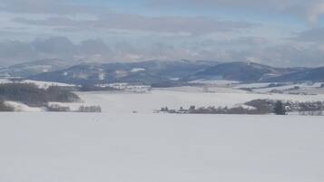 Eine verschneite Landschaft mit einem Dorf und Bergen im Hintergrund.