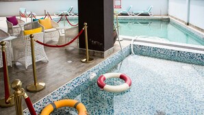 A pool area with a tiled floor, lounge chairs, and a red rope barrier.