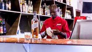 A bar with a counter, a bottle of liquor, and a glass.