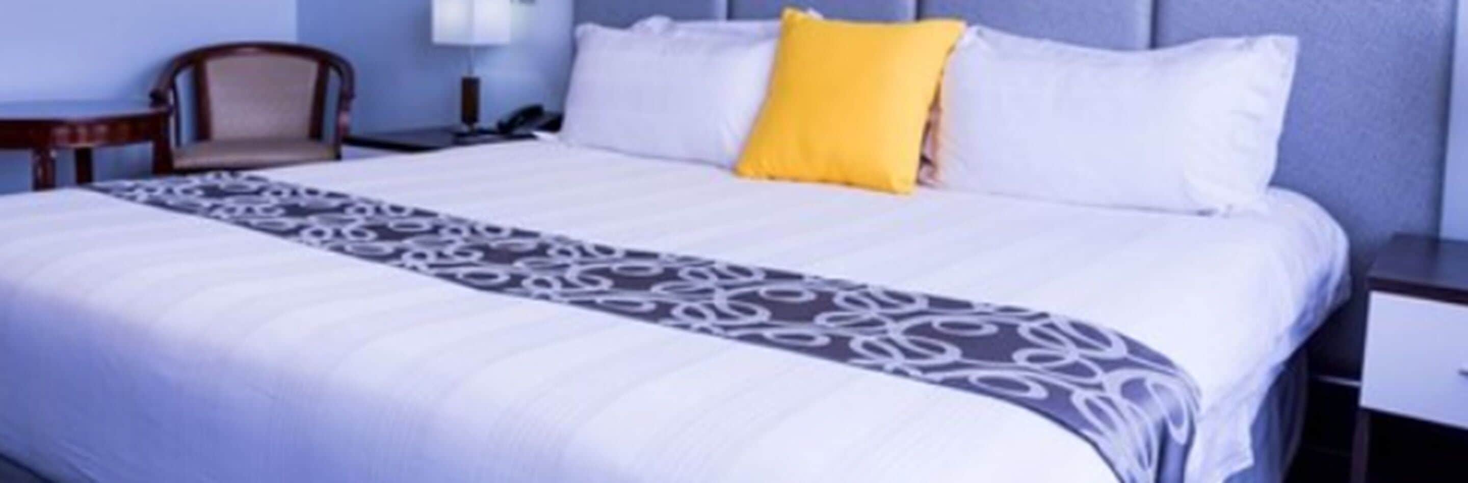 A hotel room with a bed, a nightstand, a chair, and a lamp.