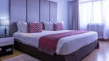 Una habitación de hotel moderna con una cama grande, una mesita de noche y una mesilla.