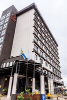 A hotel with a modern design, featuring a prominent entrance and multiple flags.