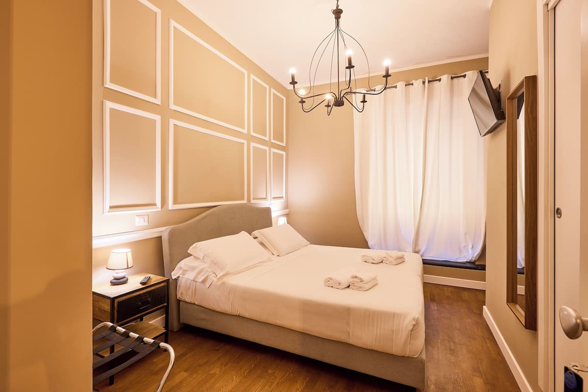 Une chambre à coucher bien rangée, avec un lit, une table de chevet, une lampe et un lustre.