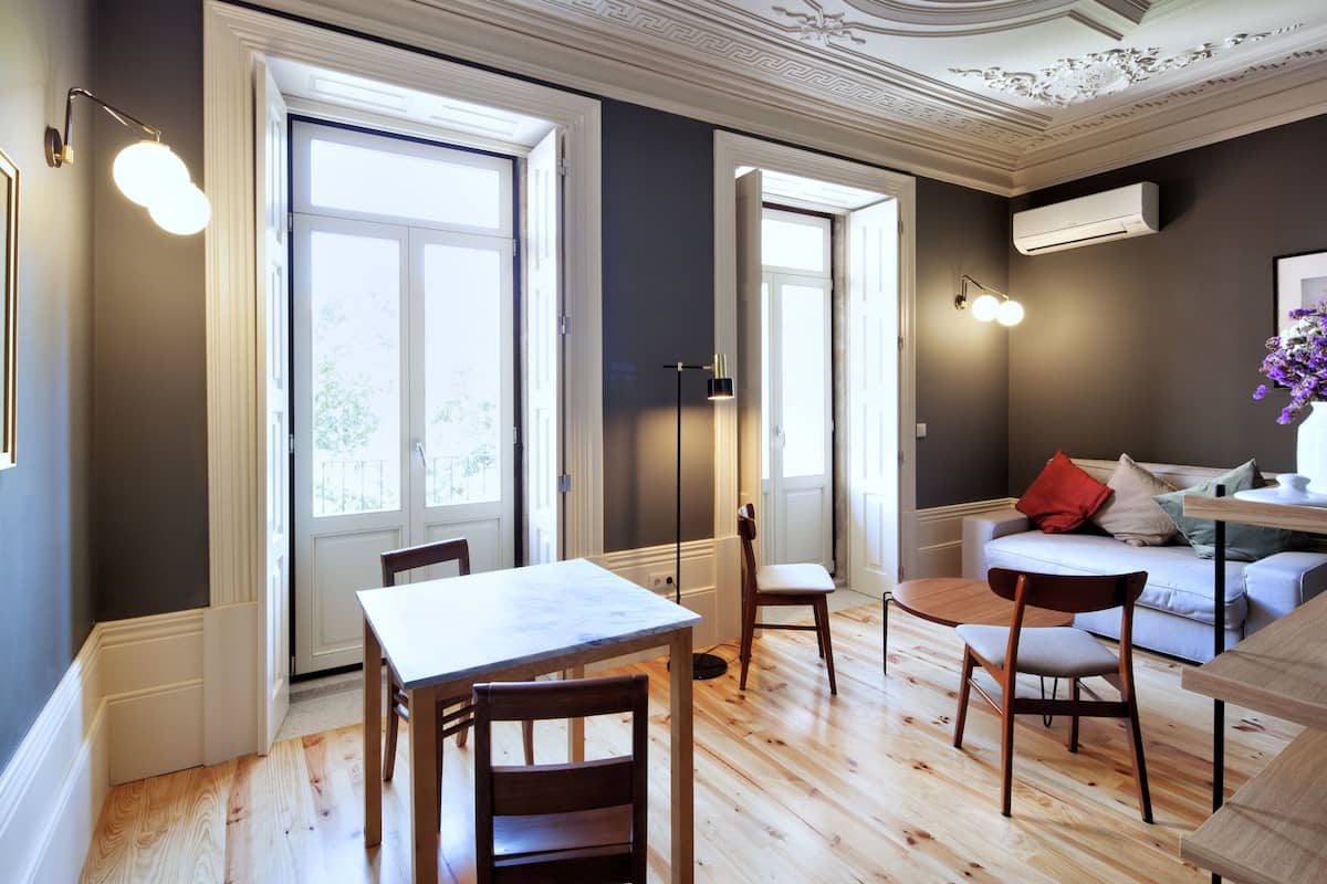 Un espace repas comprenant une table et des chaises en bois, un canapé et un plafond décoratif.