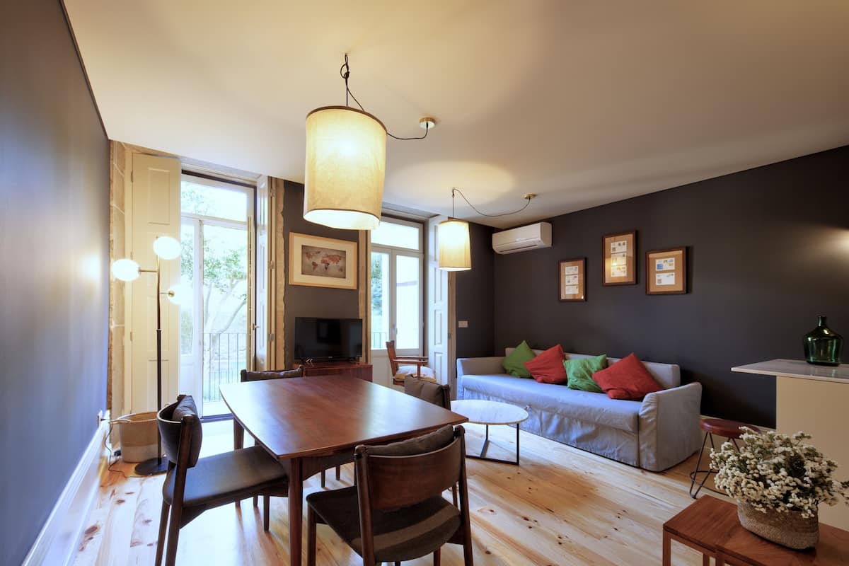 Un salon moderne avec une table à manger en bois, des chaises, un canapé et un téléviseur.