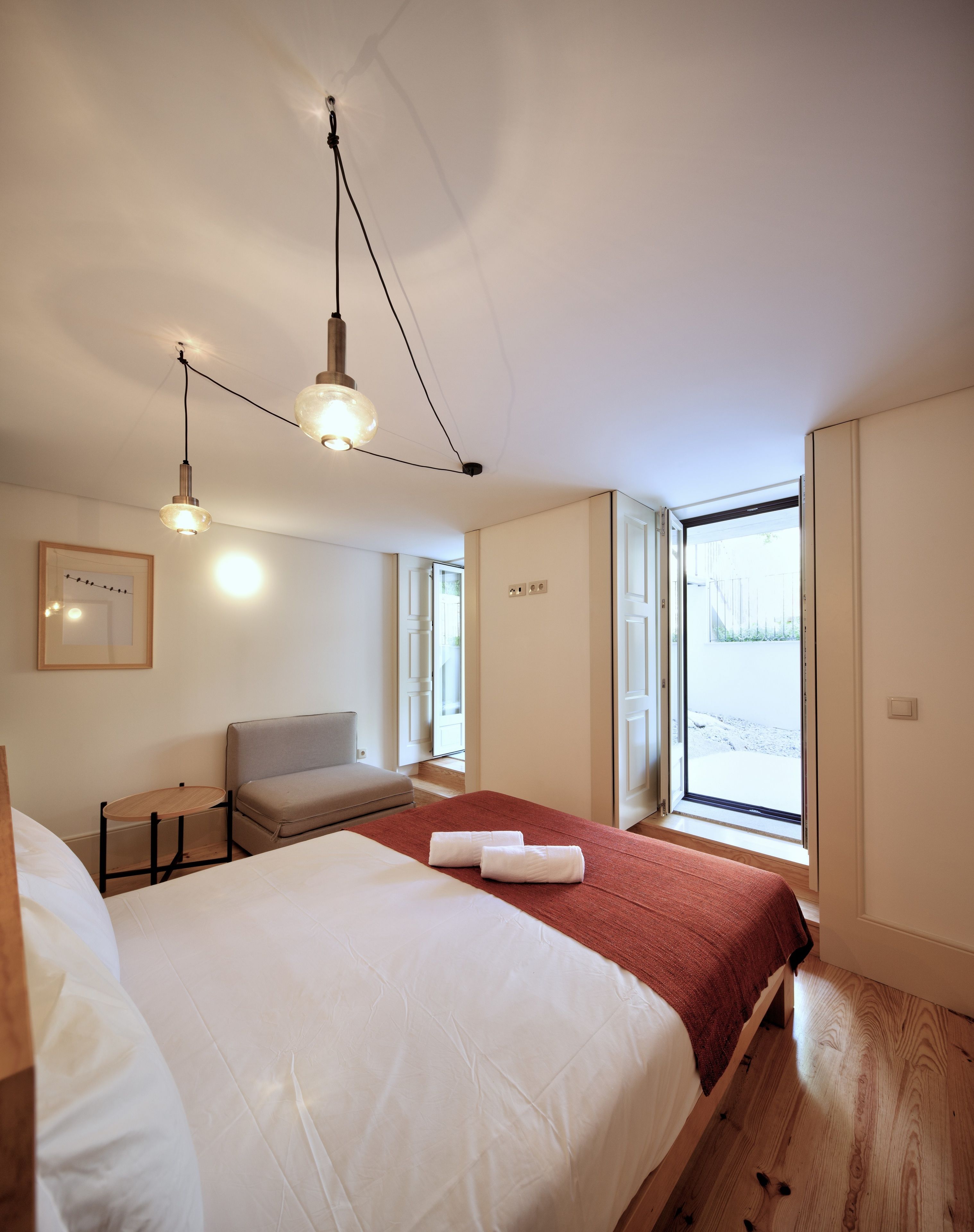 A modern hotel room with a large bed, a seating area, and a view through the window.