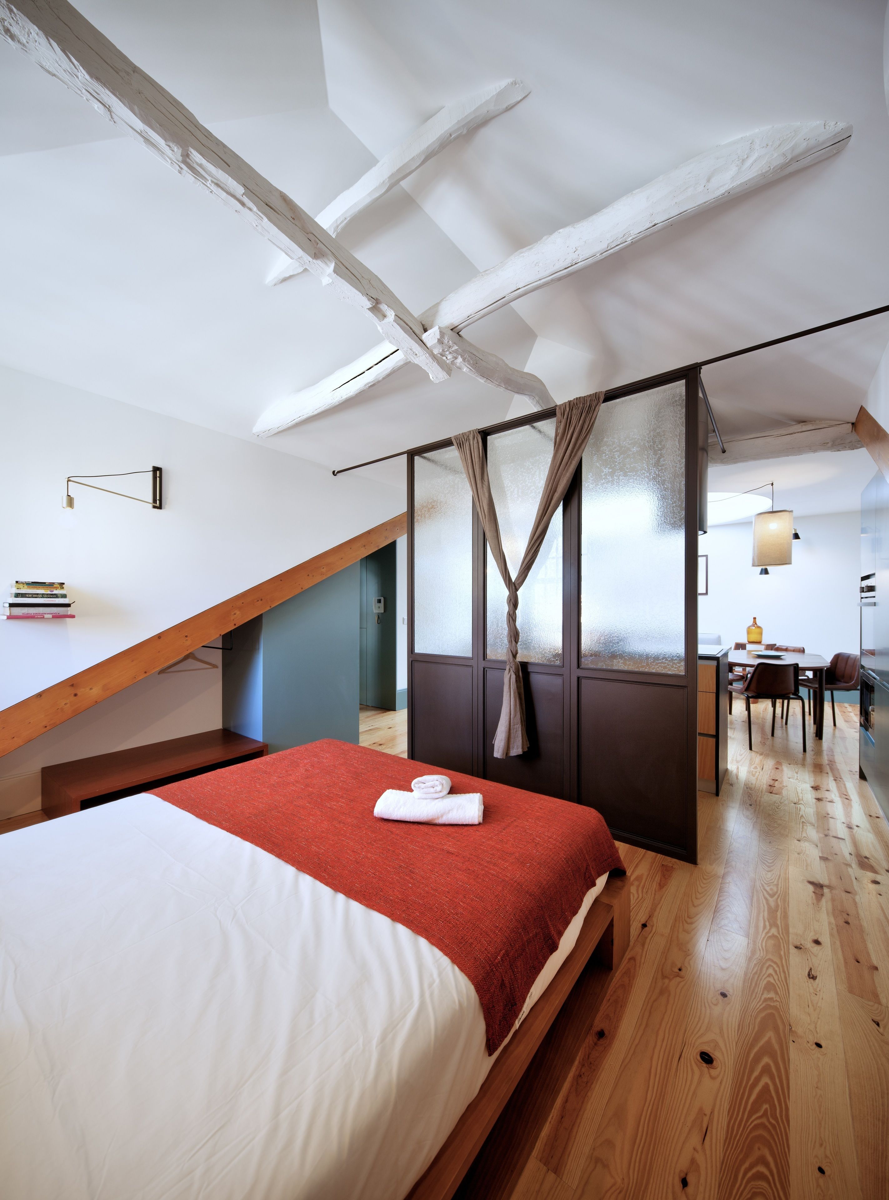 Een moderne hotelkamer met een vide, houten balken, een eethoek en uitzicht op de stad.