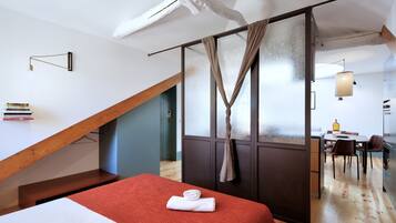 Een moderne hotelkamer met een vide, houten balken, een eethoek en uitzicht op de stad.