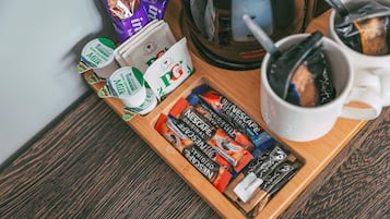 Ein Tablett mit Kaffeekapseln, einer Kaffeemaschine und einer Tasse auf einem Holztisch.