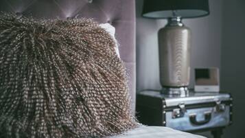 A tufted headboard, a lamp, and a suitcase in a hotel room.