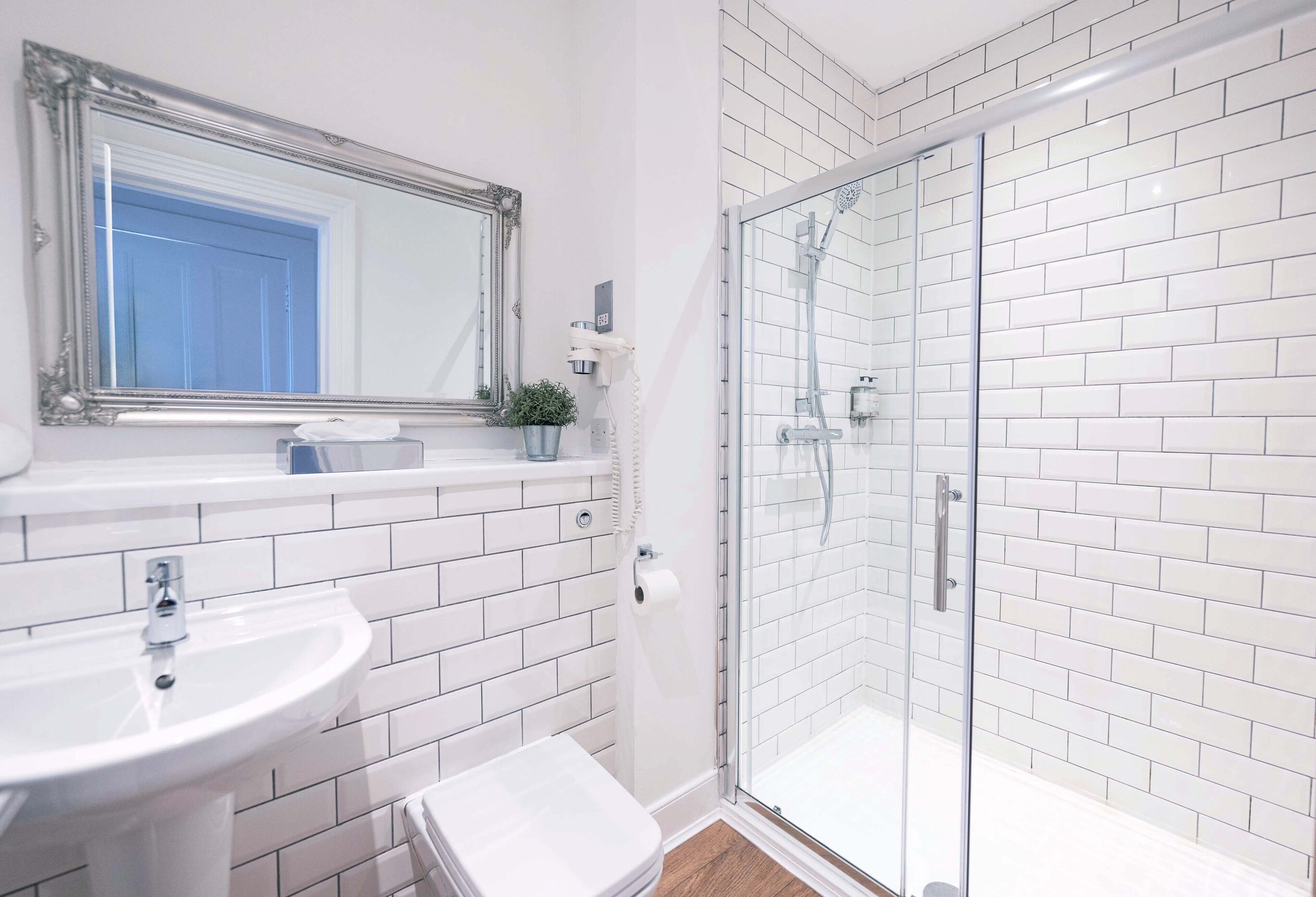 Une salle de bain avec un lavabo blanc, des toilettes et une douche à parois de verre.