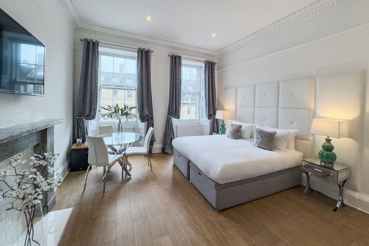 Una habitación de hotel moderna con una cama grande, una mesa de comedor y una chimenea.