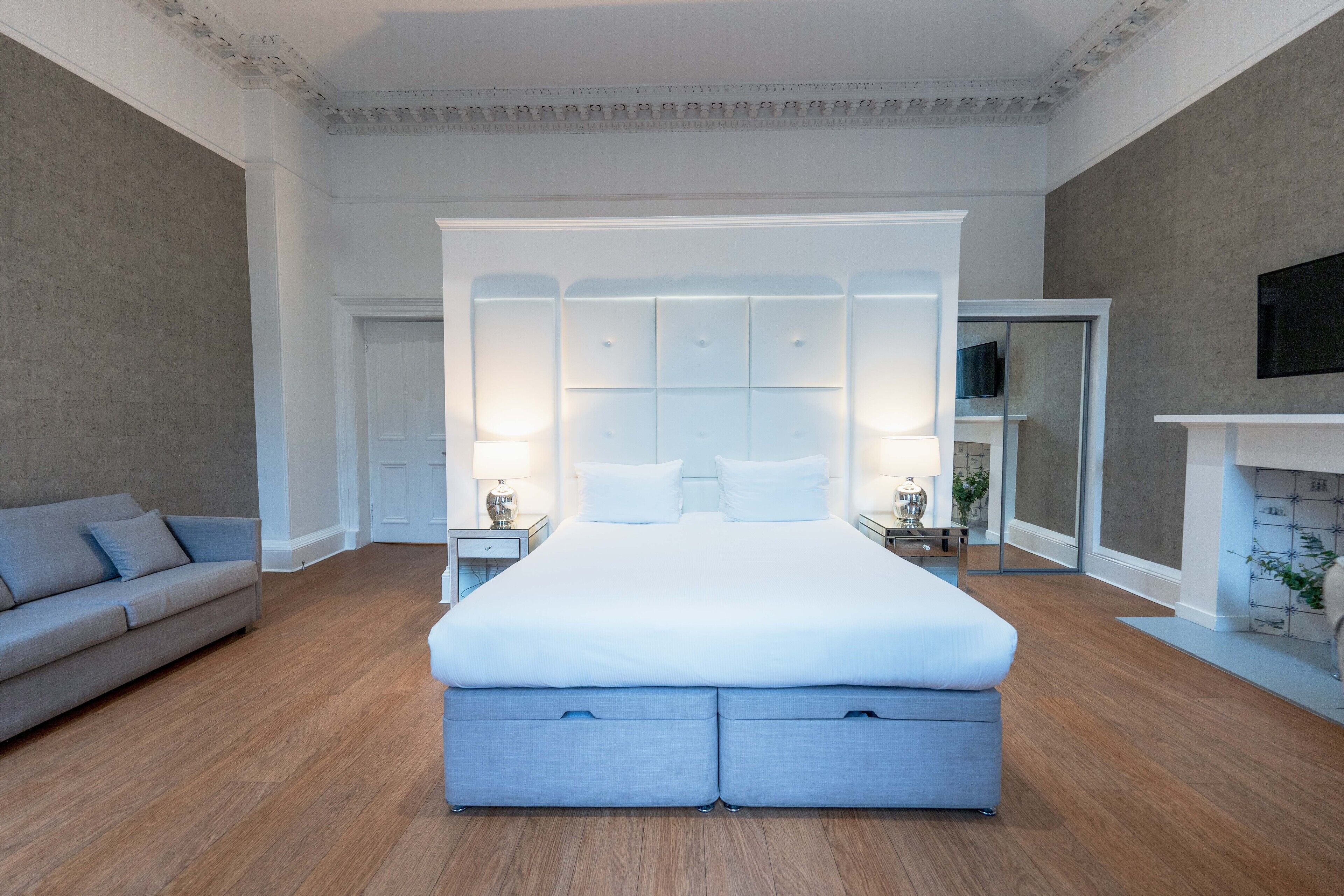 Een moderne slaapkamer met een groot bed, een bank, een televisie en een open haard.