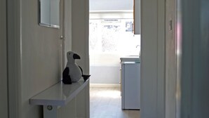 A narrow hallway with a radiator, a shelf with a black and white bird figurine, and a hanging light fixture. - Birchington Maisonette Near the Sea (Birchington)