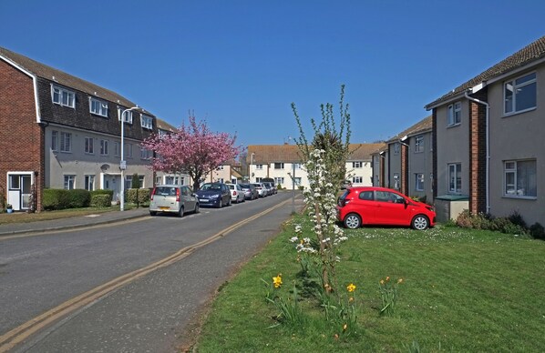 A residential street with houses, parked cars, and a clear blue sky.