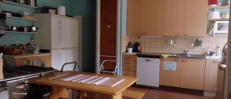 A compact kitchen with wooden cabinets, a built-in stove, and a dining table with benches.