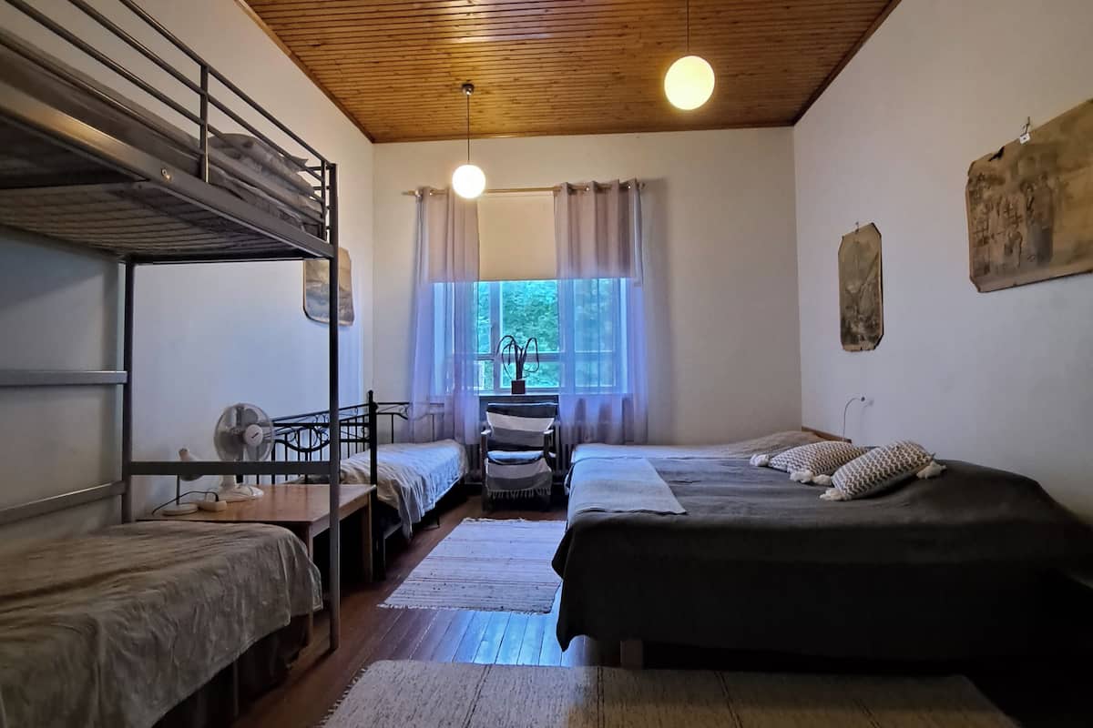 A dormitory room with bunk beds, a desk, and a chair.
