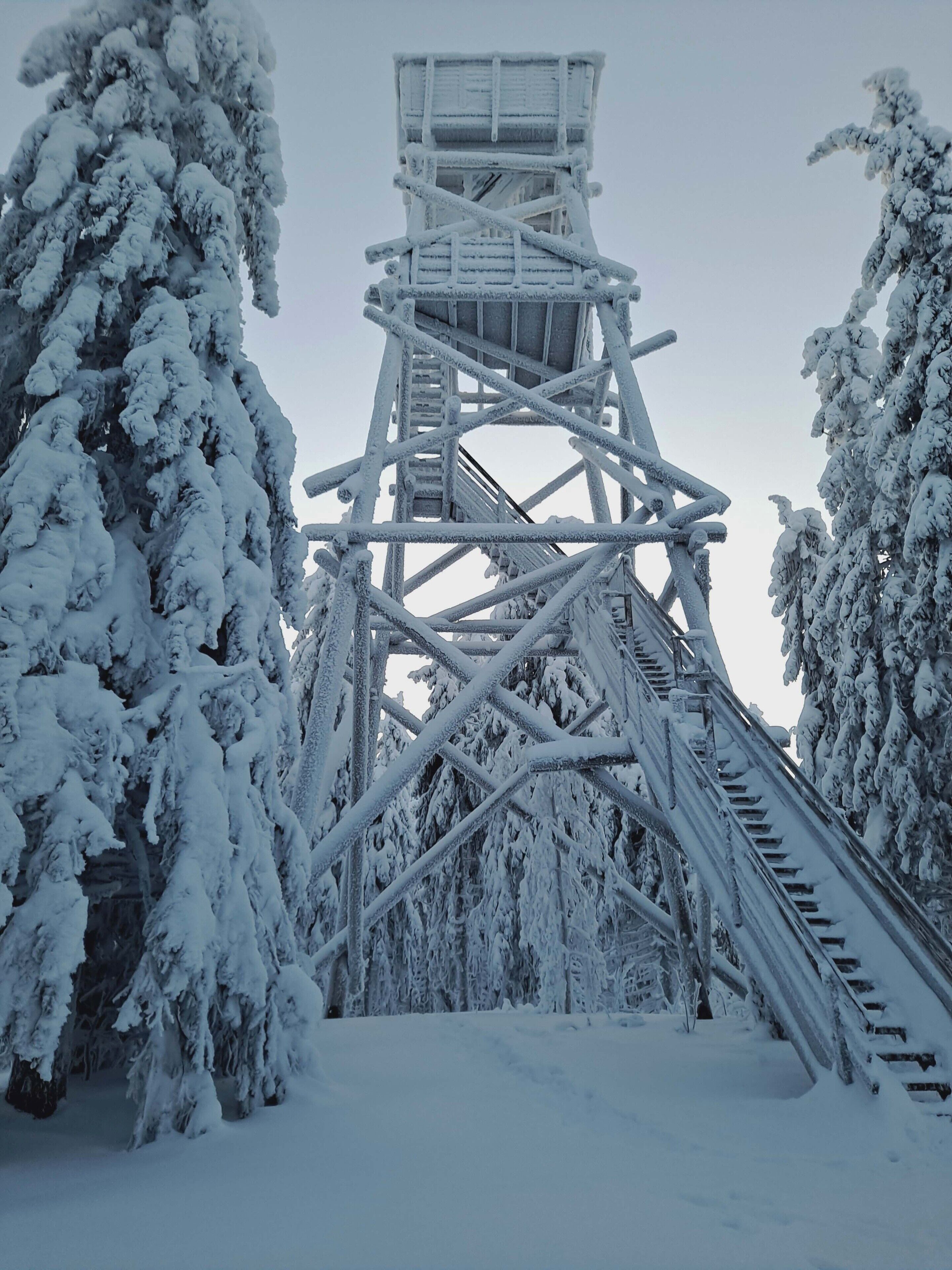 A snow-covered observation tower with a staircase leading to a viewing platform.