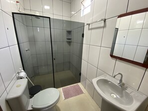 A bathroom with a toilet, sink, and shower stall.