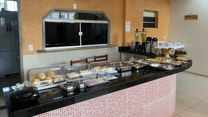Zona de bufé con diferentes opciones de comida, una ventana y un ventilador en la pared.