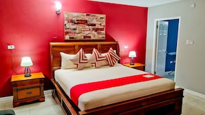 Ein Hotelzimmer mit einem hölzernen Bett, roten Wänden und einem Gemälde darüber.