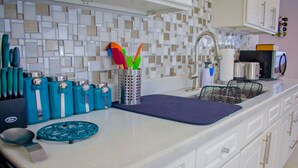 Eine moderne Küche mit weißen Schränken, einer blauen Arbeitsplatte und einer gemusterten Spritzschutzwand.