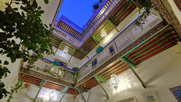 Un interior de varios niveles con balcones ornamentales, plantas colgantes e iluminación decorativa.