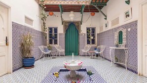 Un patio con una fuente, suelo de baldosas y zona de estar.