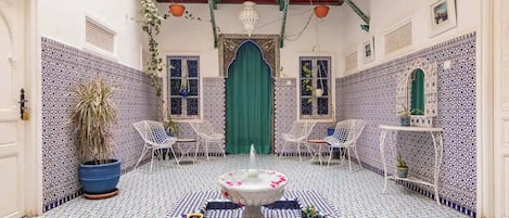 Un patio con una fuente, suelo de baldosas y zona de estar.