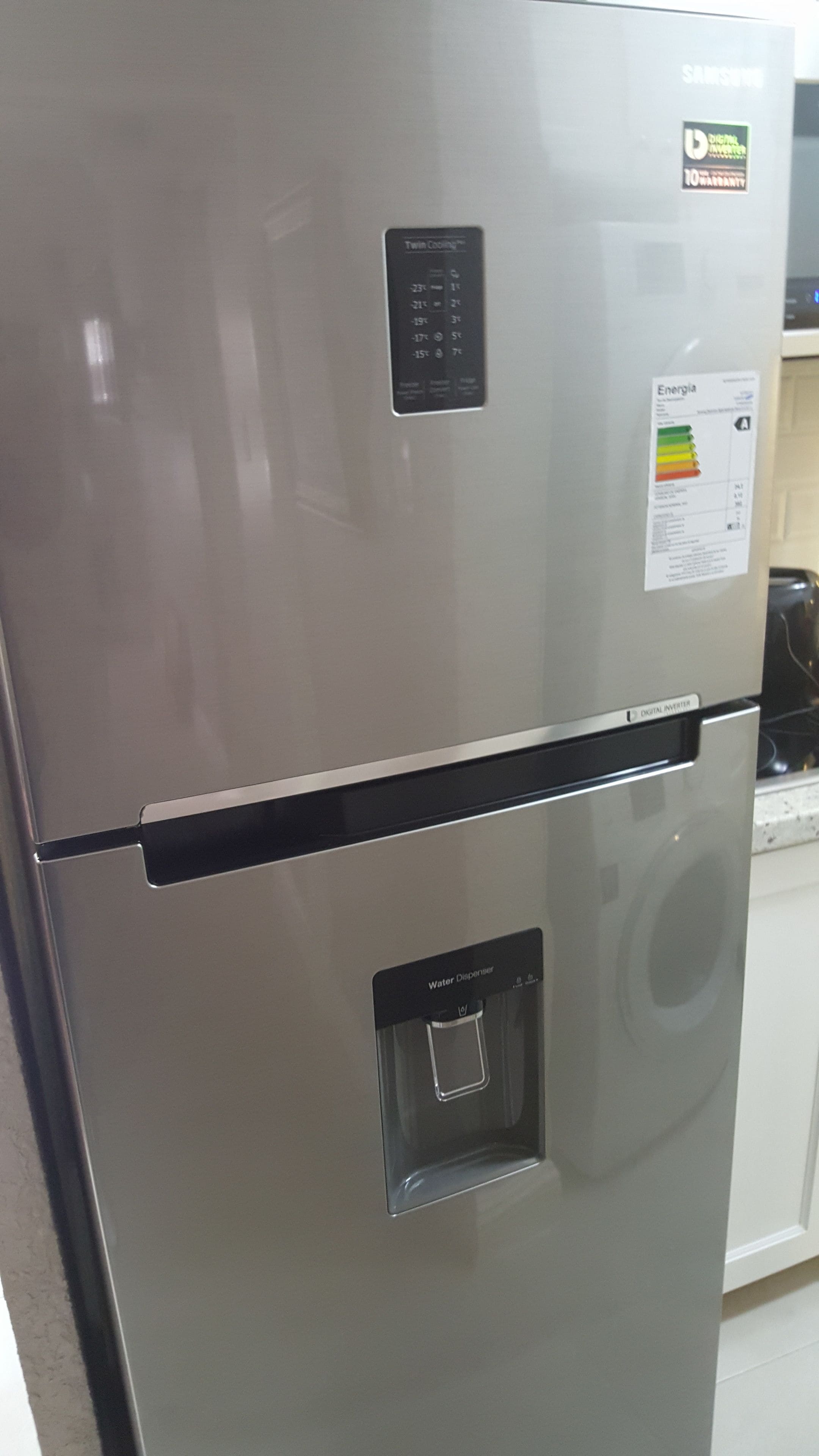 A stainless steel refrigerator with a digital display, a water dispenser, and a digital inverter label.