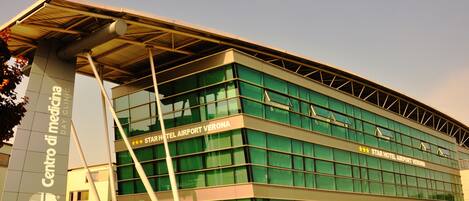 A modern building with large glass windows and a sign for the Star Hotel Airport Verona.