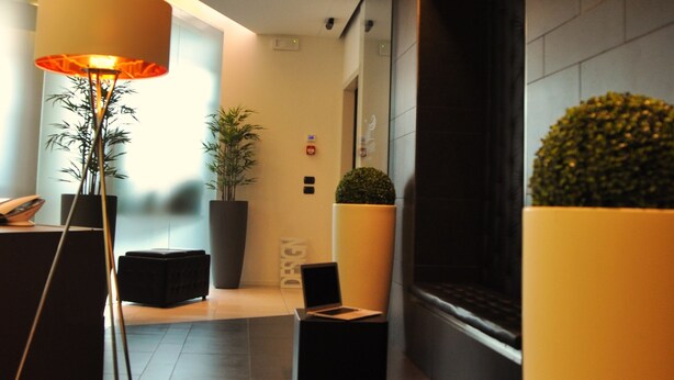 Eine moderne Lobby mit Stehlampe, Topfpflanzen und einer Rezeption.