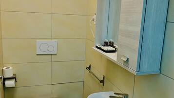 Un baño pequeño con inodoro, lavamanos y espejo.
