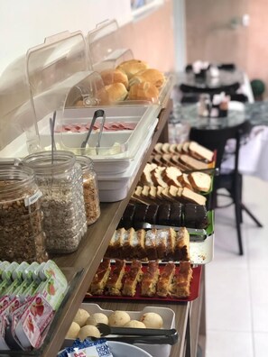 A buffet with various food items including pastries, sandwiches, and desserts. - Hotel Araçari (Aracariguama)