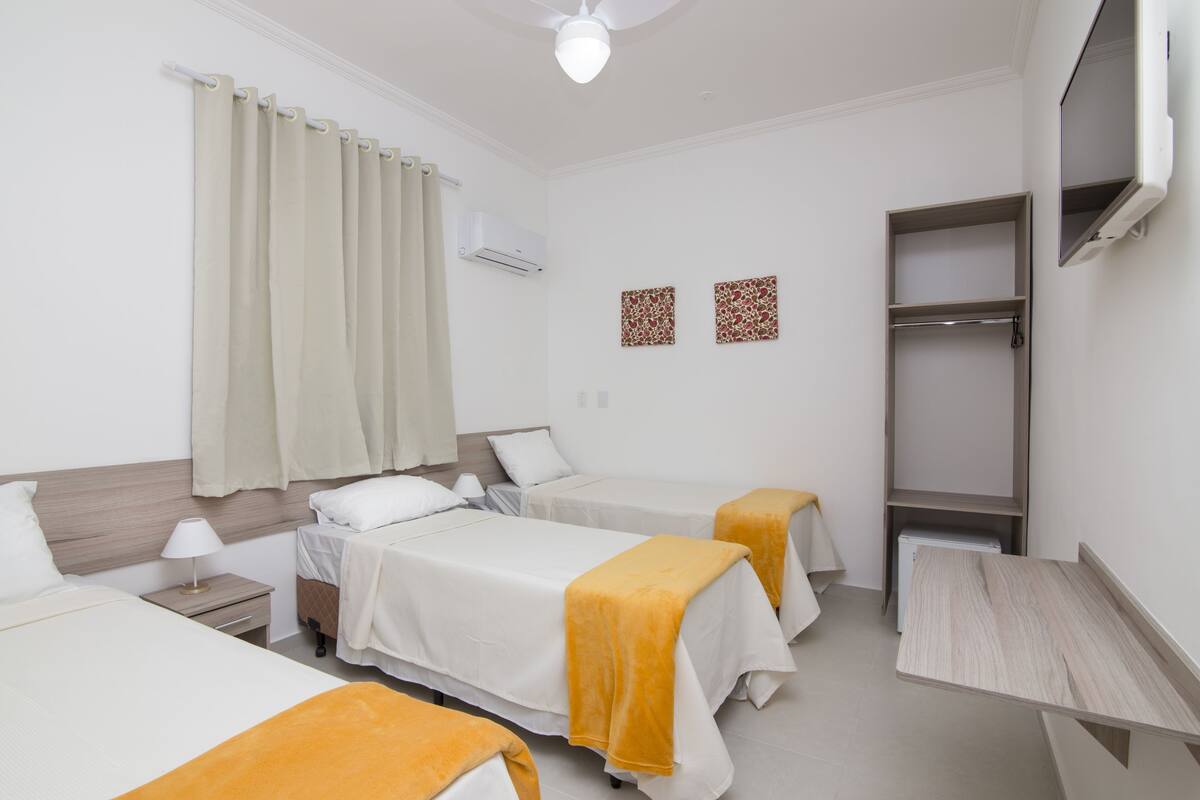 Habitación de hotel con dos camas, un escritorio, un armario y un ventilador de techo.