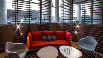 A modern interior with a red sofa, two chairs, and a round table.