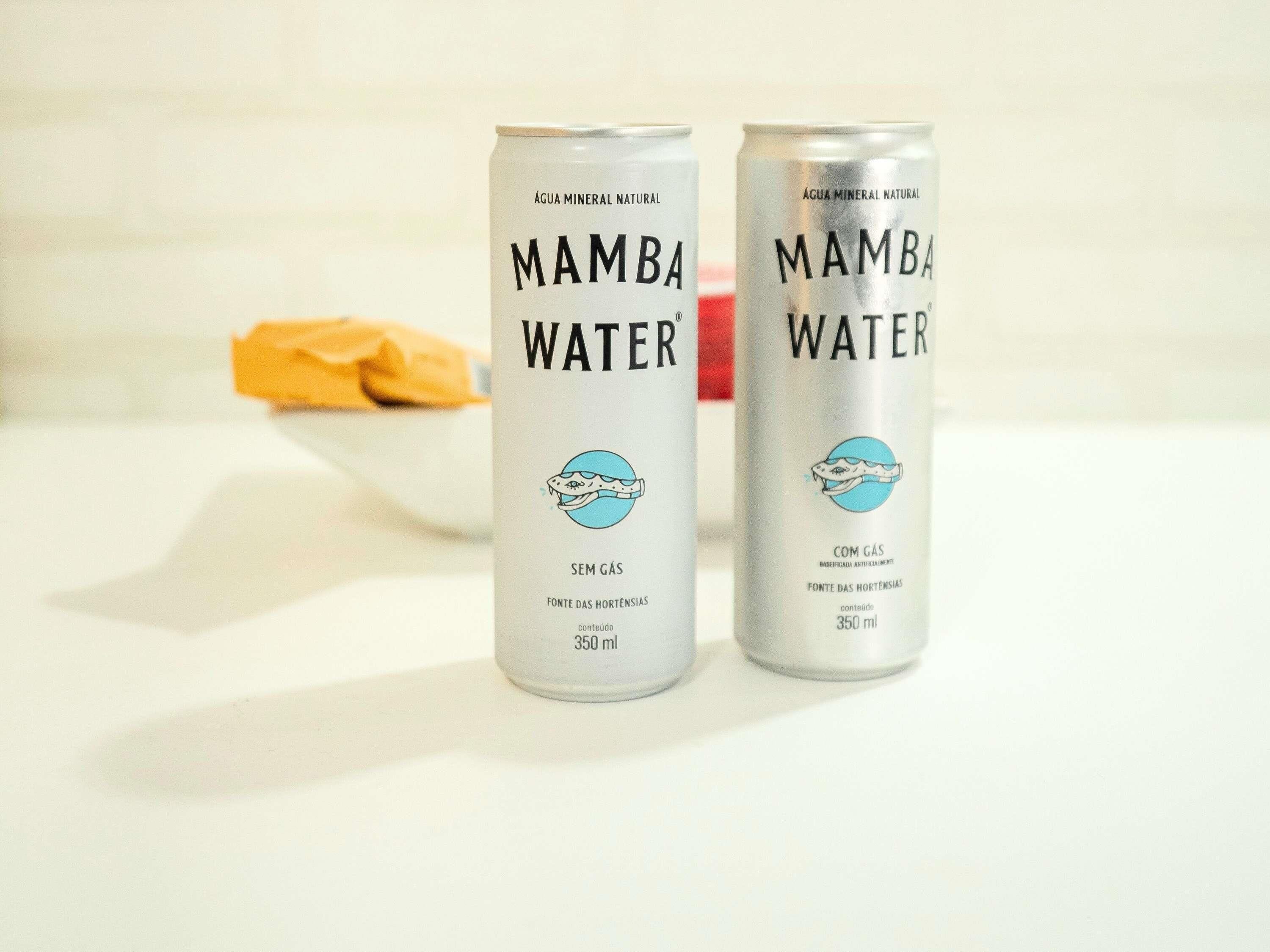 Two cans of Mamba Water on a white surface with a bowl in the background.