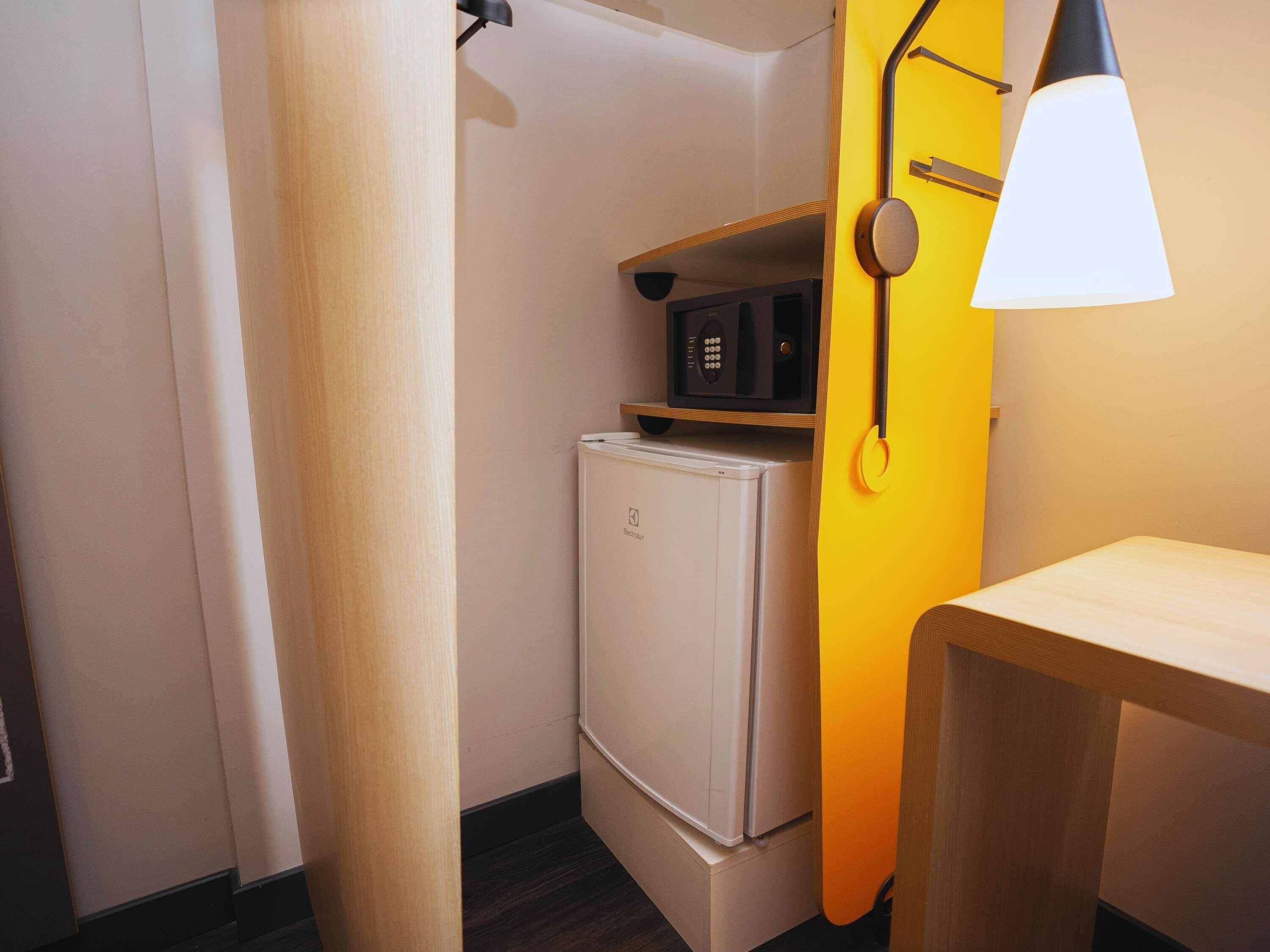A compact kitchenette with a microwave, a refrigerator, and a small table.