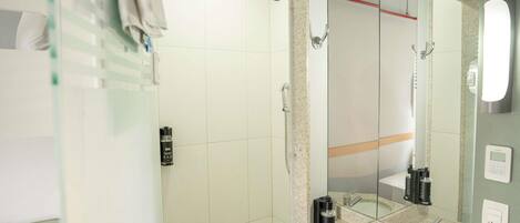 Un baño moderno con cabina de ducha de vidrio, un lavamanos con espejo y un cabezal de ducha manual.