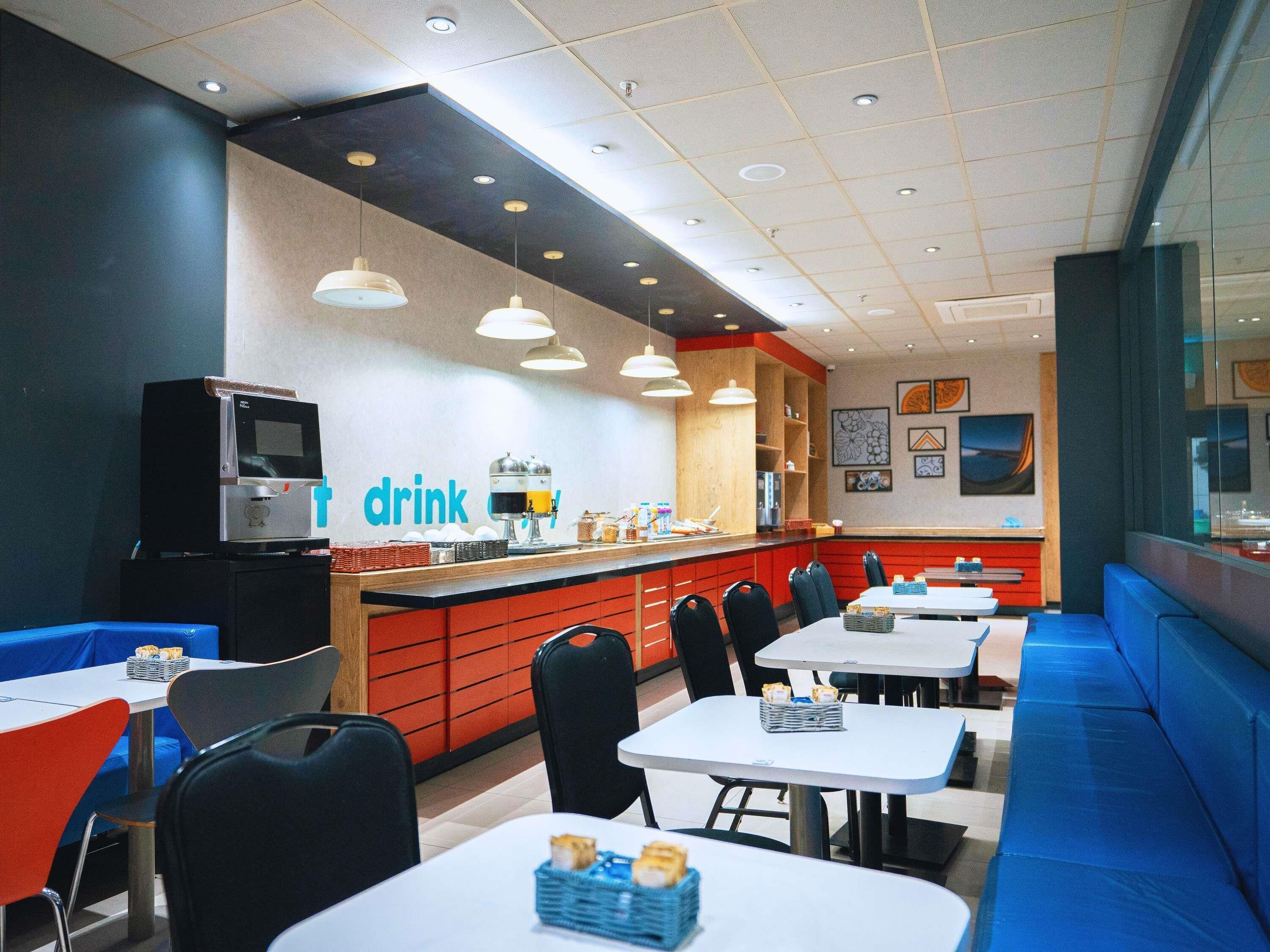 A modern cafe with a counter, seating area, and a TV.
