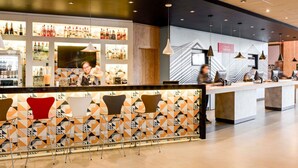 A modern bar area with a geometric patterned wall, a variety of bottles, and a counter with bar stools. - ibis budget São Bernardo do Campo (São Bernardo do Campo)