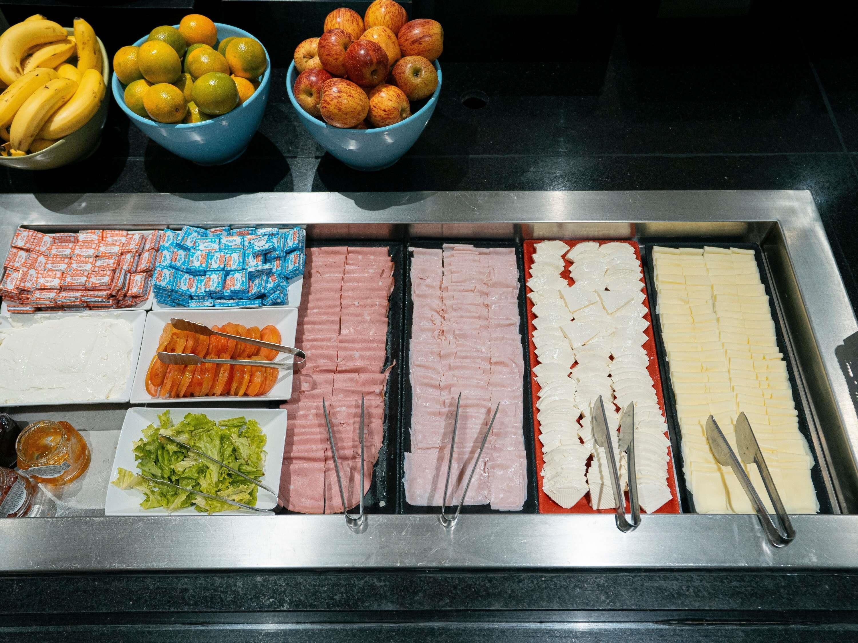 A buffet with various food items including fruits, meats, and condiments.