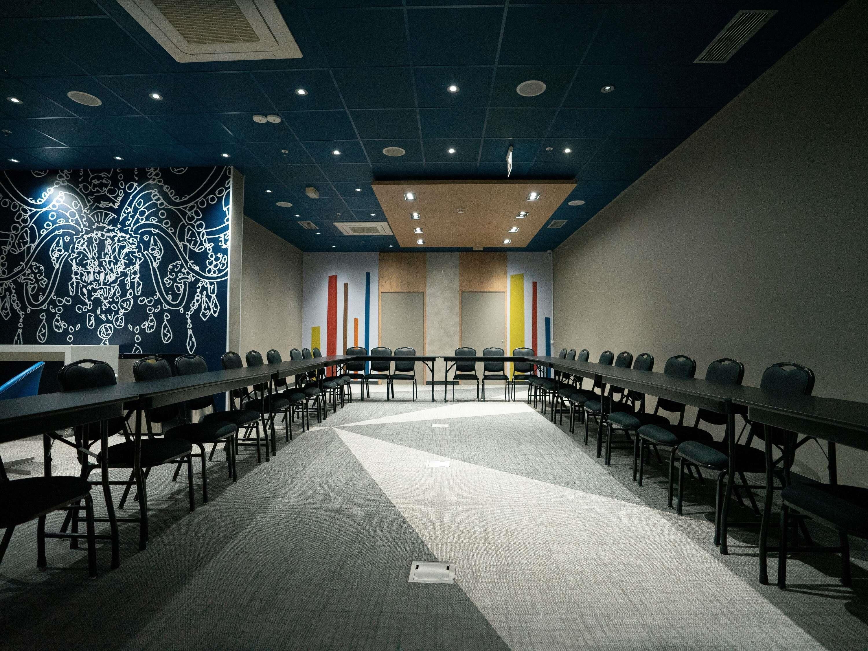 A conference room with a long table, chairs, and a patterned wall.