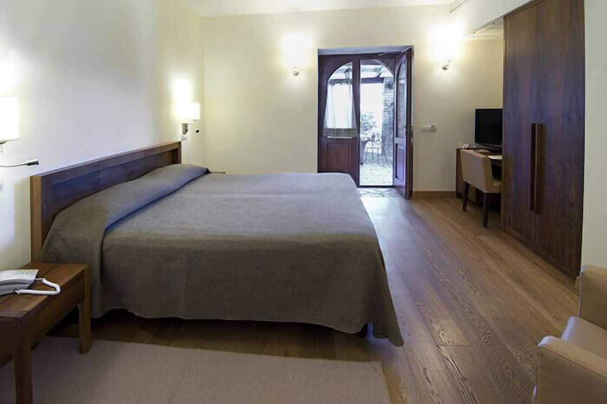 A bedroom with a large bed, bedside tables, a desk with a chair, and a wardrobe.