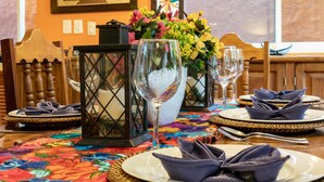 Une table à manger dressée avec des assiettes, des verres et un centre de table composé de fleurs.