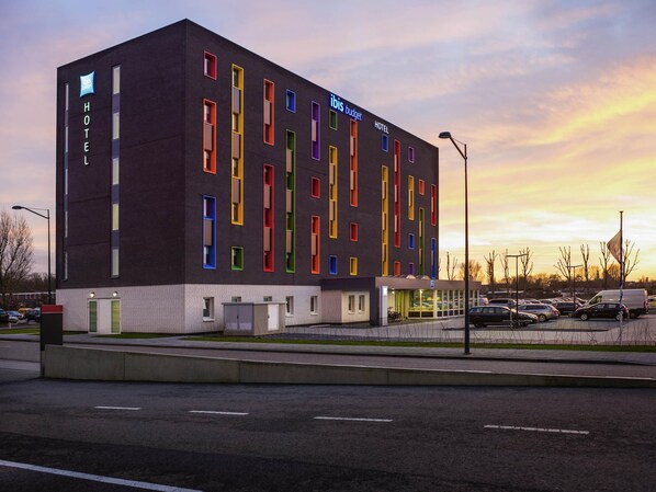 Ein modernes Hotel mit schwarzer Fassade und bunten Fensterrahmen, in der Nähe eines Parkplatzes gelegen.