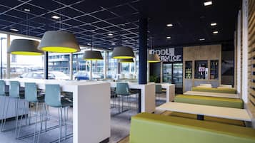Un café moderne doté d’un bar, de coins salons et offrant une vue sur la rue.
