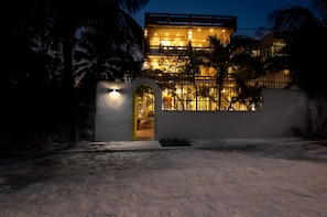 A modern hotel with a well-lit entrance, a covered outdoor area, and a view of the surrounding landscape. - Casa Agua Azul (Puerto Morelos)