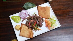 A plate of food with beef, vegetables, and bread on a wooden table. - Hotel Embassy (Nairobi)