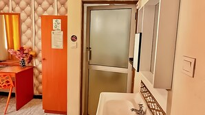 A modern bathroom with a white sink, a mirror, and a frosted glass door. - Hotel Embassy (Nairobi)